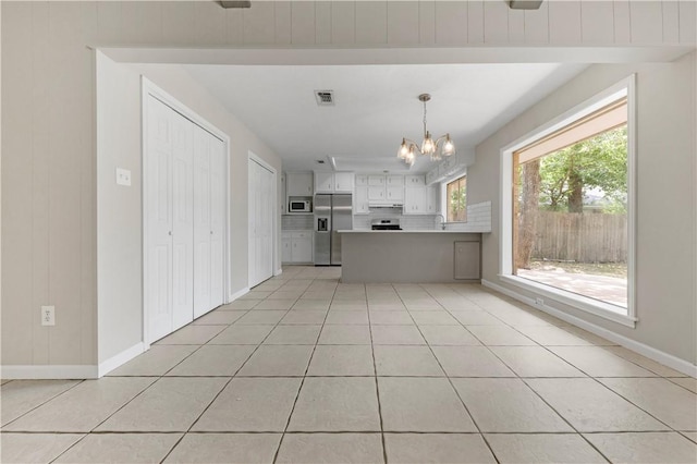 2008 Rayburn Ct, College Station, TX 77840 - kitchen with stainless steel fridge, white microwave, a chandelier, light tile patterned flooring, and a peninsula