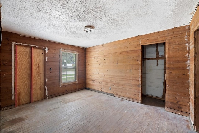 104 N Randolph Ave, Bryan, TX 77803 - unfurnished room featuring wood-type flooring, wood walls, and a textured ceiling