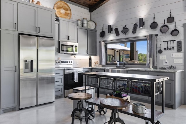 1923 County Road 202, Caldwell, TX 77836 - kitchen with stainless steel appliances, vaulted ceiling, a sink, gray cabinets, and concrete floors