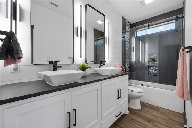 1923 County Road 202, Caldwell, TX 77836 - full bathroom featuring toilet, double vanity, wood finished floors, and bath / shower combo with glass door