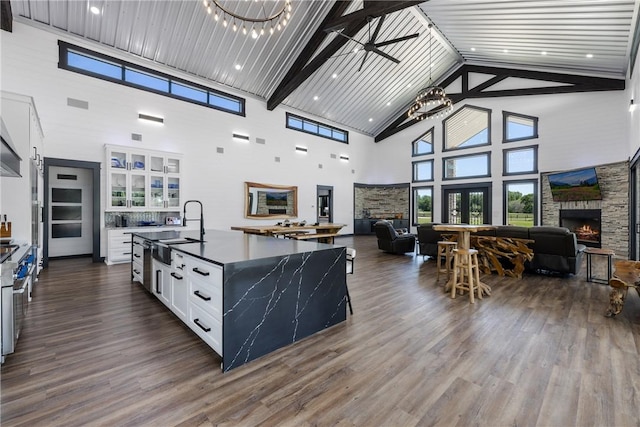 1923 County Road 202, Caldwell, TX 77836 - kitchen featuring a sink, high vaulted ceiling, a stone fireplace, open floor plan, and white cabinetry