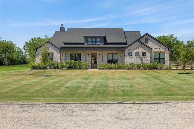 view of front of home with a standing seam roof, a front yard, metal roof, and a chimney