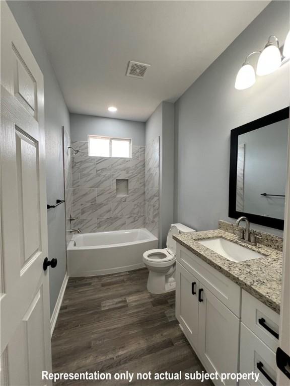 full bathroom with vanity, toilet, hardwood / wood-style floors, and tiled shower / bath