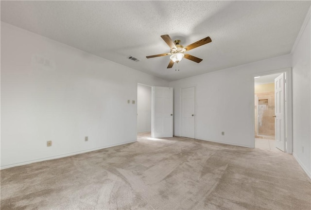 unfurnished bedroom with ceiling fan, a textured ceiling, connected bathroom, and light colored carpet