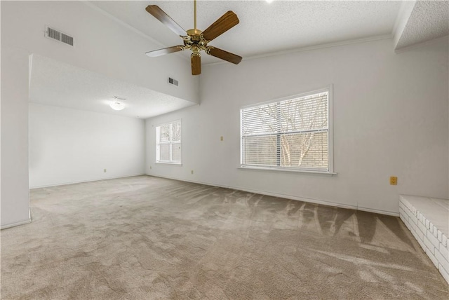 carpeted spare room with crown molding, ceiling fan, a textured ceiling, and a towering ceiling