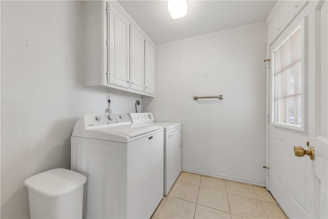 washroom with light tile patterned floors, washing machine and clothes dryer, a textured ceiling, cabinets, and crown molding