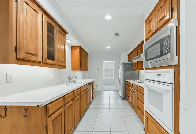 kitchen with stainless steel microwave, light tile patterned flooring, sink, and oven