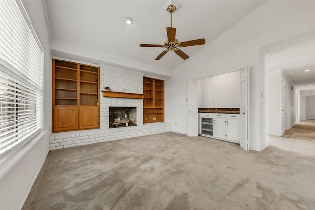 unfurnished living room featuring ceiling fan, a brick fireplace, light colored carpet, and lofted ceiling