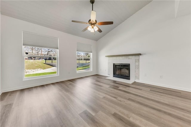 unfurnished living room with light hardwood / wood-style floors, vaulted ceiling, ceiling fan, and a fireplace