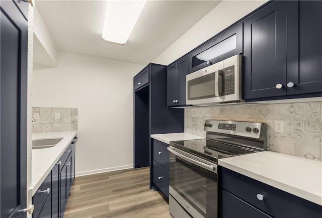 kitchen with hardwood / wood-style flooring, sink, stainless steel appliances, and backsplash