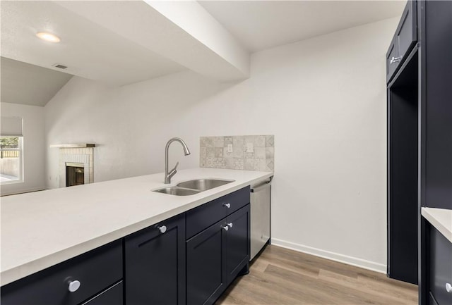 kitchen with light hardwood / wood-style floors, sink, stainless steel dishwasher, vaulted ceiling, and tasteful backsplash