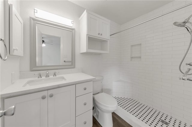 bathroom with vanity, tiled shower, and toilet