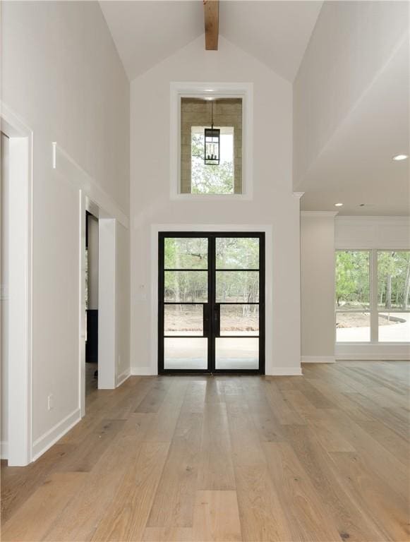 interior space featuring beam ceiling, french doors, high vaulted ceiling, and light hardwood / wood-style flooring