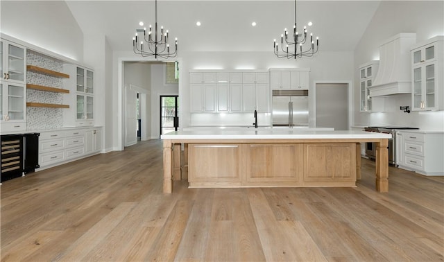 kitchen featuring light wood-type flooring, a breakfast bar, premium appliances, white cabinetry, and a large island