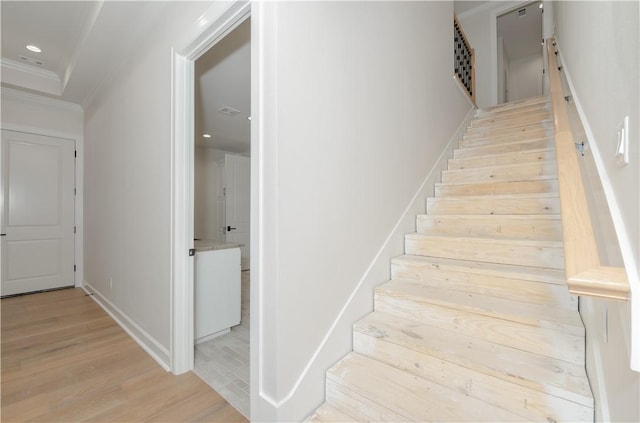 stairs with wood-type flooring and ornamental molding