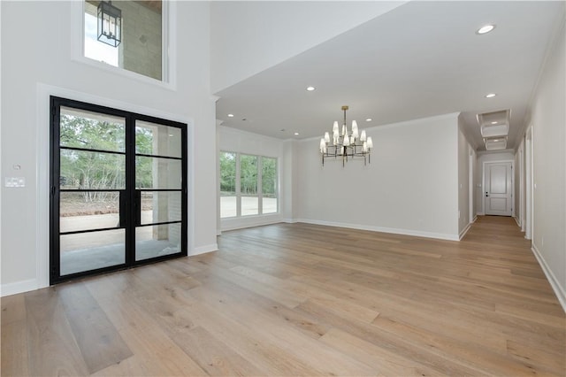 unfurnished room featuring light wood-type flooring, an inviting chandelier, and a wealth of natural light