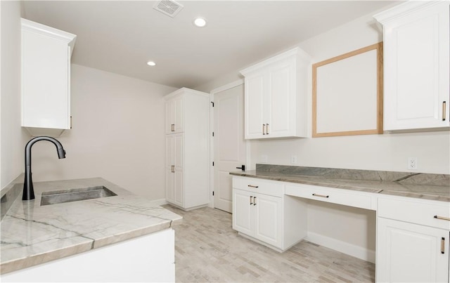 kitchen with white cabinets, light hardwood / wood-style flooring, and sink