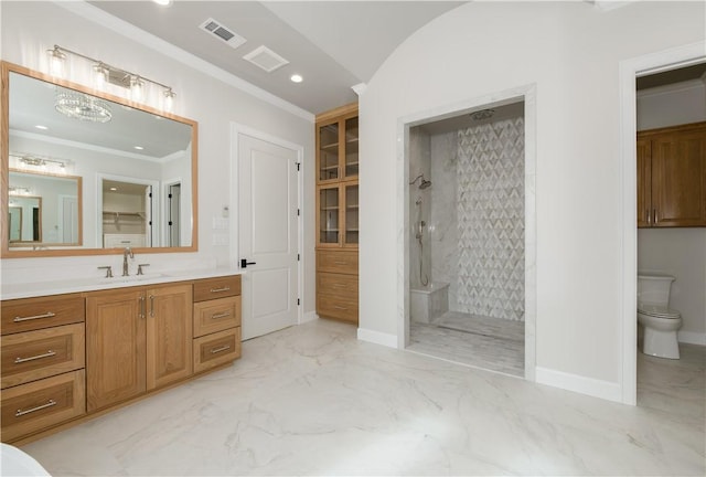 bathroom with vanity, toilet, tiled shower, and crown molding