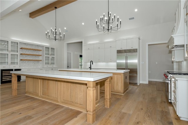 kitchen with appliances with stainless steel finishes, light wood-type flooring, a kitchen breakfast bar, a spacious island, and white cabinets