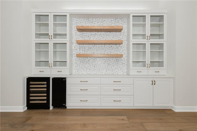 bar with white cabinets, wood-type flooring, and beverage cooler