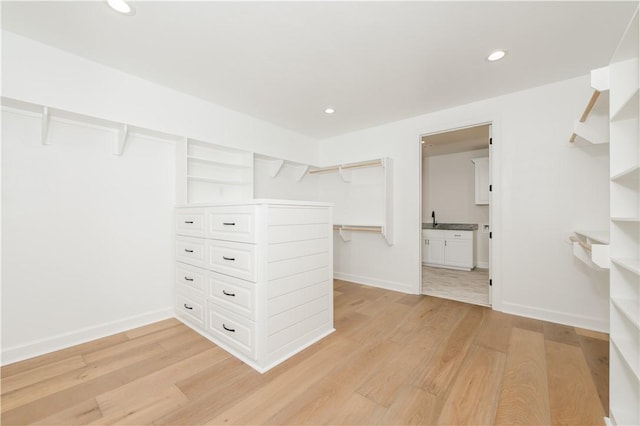 walk in closet with light hardwood / wood-style floors