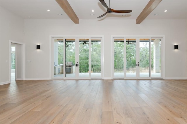 unfurnished living room with a healthy amount of sunlight, light wood-type flooring, and french doors