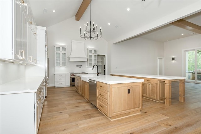 kitchen featuring appliances with stainless steel finishes, sink, a large island with sink, beam ceiling, and light hardwood / wood-style floors