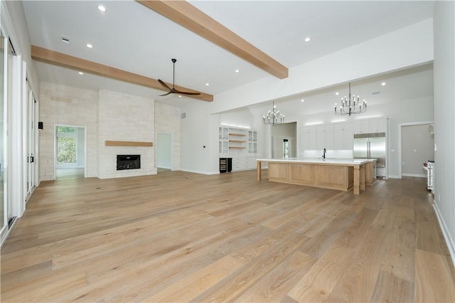 unfurnished living room featuring beam ceiling, a fireplace, and light hardwood / wood-style flooring