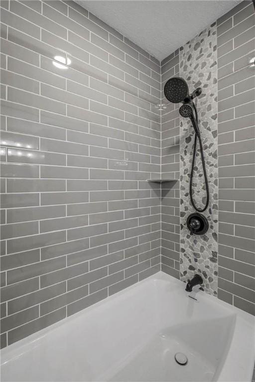 bathroom with a textured ceiling and tiled shower / bath combo