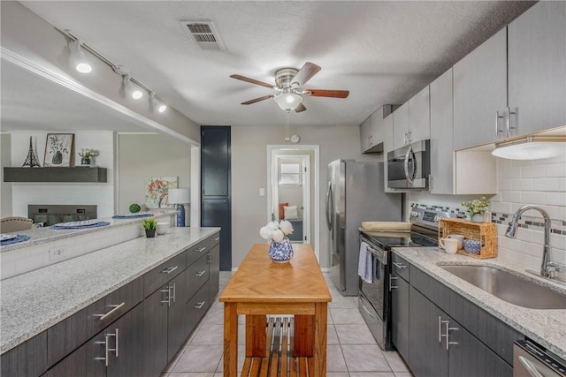 kitchen with sink, a textured ceiling, appliances with stainless steel finishes, light tile patterned flooring, and white cabinetry