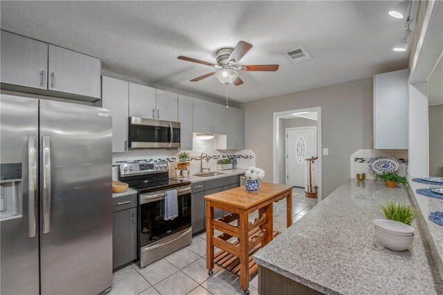 kitchen with tasteful backsplash, sink, light tile patterned flooring, and stainless steel appliances