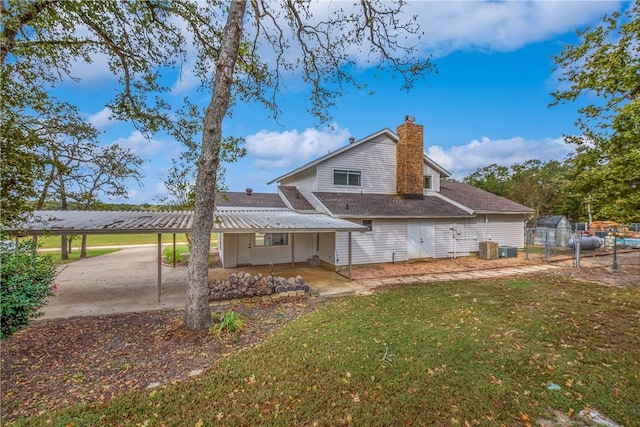 rear view of house featuring a yard, a carport, and central air condition unit