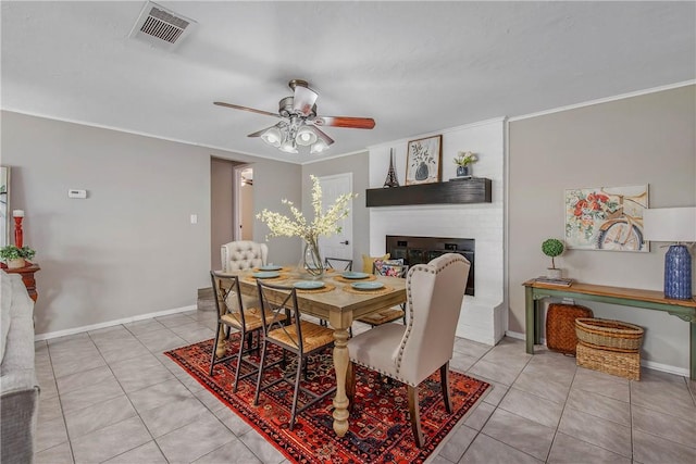 tiled dining space featuring a large fireplace and ceiling fan