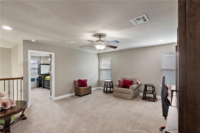 living area with ceiling fan and light carpet