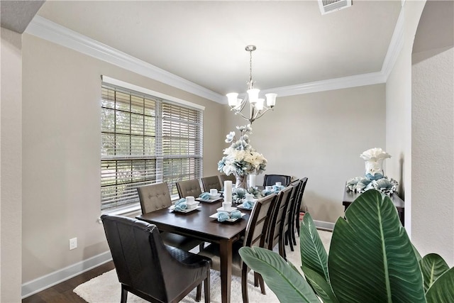 dining space with wood-type flooring, an inviting chandelier, and ornamental molding