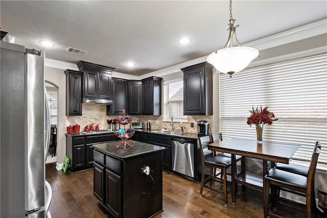 kitchen with sink, stainless steel appliances, dark hardwood / wood-style floors, a kitchen island, and ornamental molding