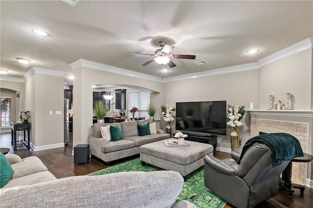 living room featuring a fireplace, dark hardwood / wood-style flooring, ceiling fan, and crown molding