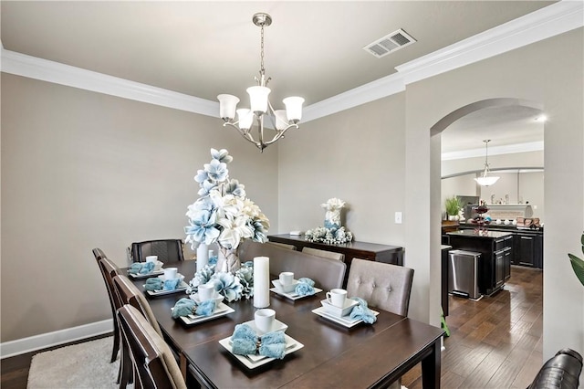 dining area with ornamental molding, dark wood-type flooring, and an inviting chandelier