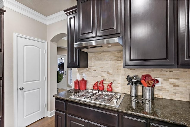 kitchen with stainless steel gas cooktop, dark hardwood / wood-style floors, backsplash, dark stone counters, and ornamental molding