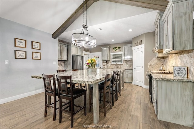 dining room featuring lofted ceiling with beams, light wood-type flooring, sink, and a chandelier