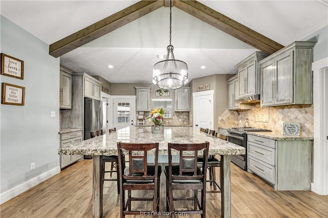 kitchen with decorative backsplash, appliances with stainless steel finishes, light wood-type flooring, and pendant lighting