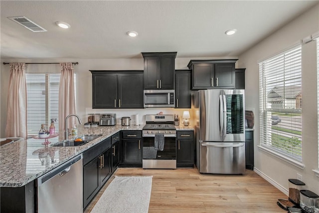 808 Mineral Wells Ln, College Station, TX 77845 - kitchen with stainless steel appliances, healthy amount of natural light, light stone countertops, dark cabinets, and recessed lighting