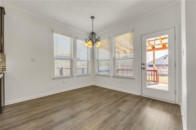 unfurnished dining area with crown molding, dark hardwood / wood-style floors, and a chandelier