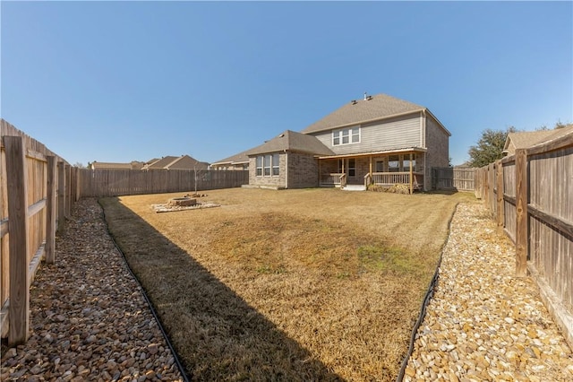 rear view of property with a yard and a fire pit