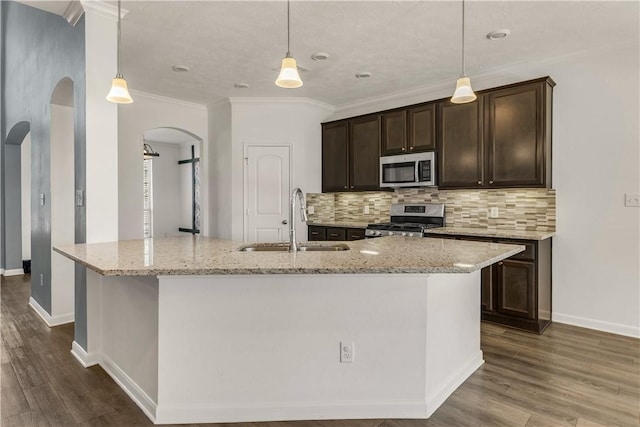 kitchen featuring appliances with stainless steel finishes, sink, pendant lighting, and a kitchen island with sink