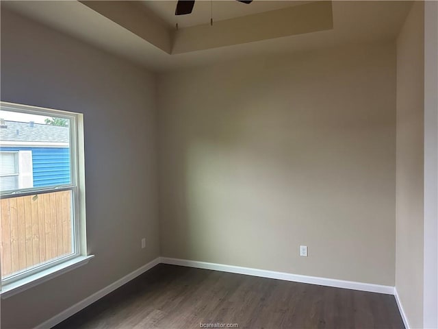 spare room with ceiling fan, dark hardwood / wood-style floors, and a raised ceiling