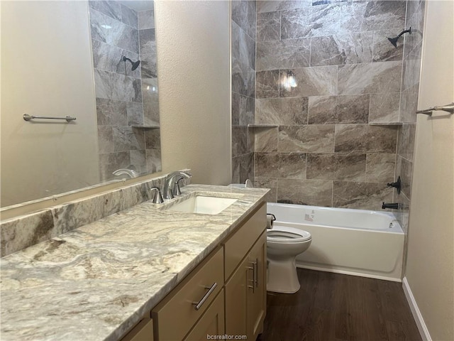 full bathroom with hardwood / wood-style flooring, toilet, tiled shower / bath, and vanity