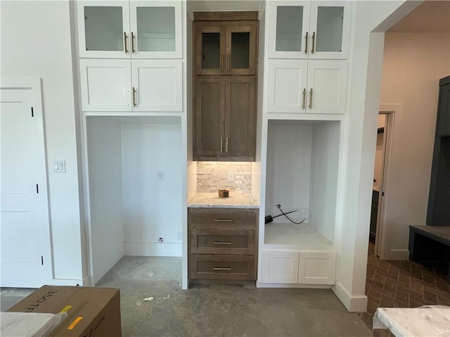 interior space featuring light stone countertops, concrete floors, and white cabinets