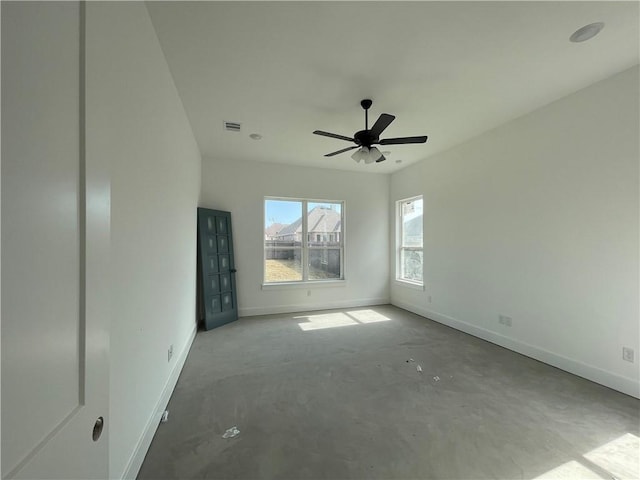 spare room featuring concrete flooring, visible vents, ceiling fan, and baseboards