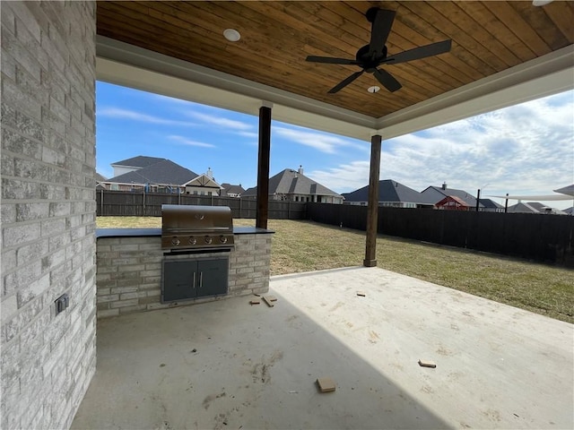 view of patio / terrace with an outdoor kitchen, area for grilling, ceiling fan, a fenced backyard, and a residential view